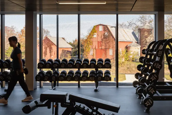 Dumbbell racks in a weight room with windows looking out on a red barn