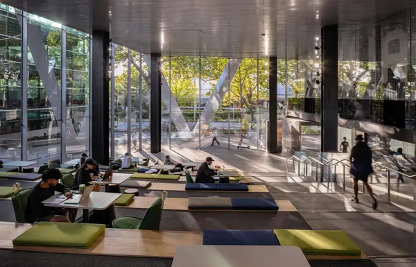 Students studying on lounge seating beside a glass wall