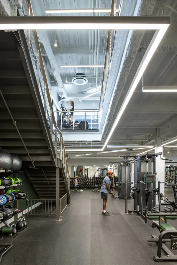 Two-level weight room with a staircase and industrial lighting